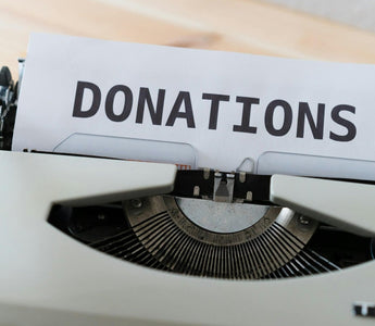 Vintage typewriter holding a sheet of paper with the word “DONATIONS” in bold black letters.