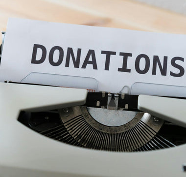 Vintage typewriter holding a sheet of paper with the word “DONATIONS” in bold black letters.