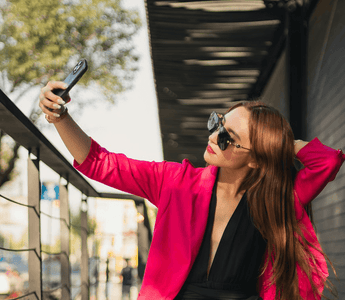 Young woman in a pink jacket taking a selfie outdoors, illustrating social media-driven shopping and fashion returns culture.