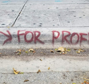 Graffiti on a pavement reading “For Profit” with an arrow, symbolising the focus on profit over long-term business strength.