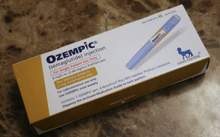 Close-up of an Ozempic injection medication box on a marble surface, showing the branded packaging and injectable pen used for diabetes and weight-loss treatment.