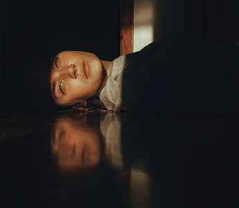 Woman resting on the floor in a dimly lit office, representing workplace wellbeing and the growing acceptance of rest at work.