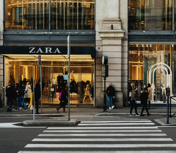 Shoppers outside a Zara store with large display windows and a pedestrian crossing in the foreground.