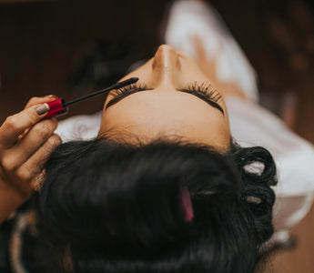 Close-up of a woman having mascara applied during a beauty treatment, representing the global cosmetics and fragrance industry discussed in the article.