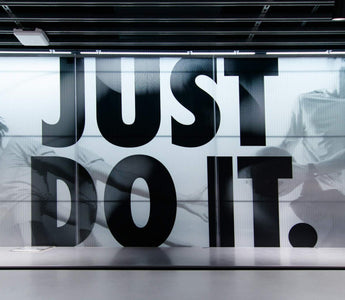 Nike store interior with a large “Just Do It” slogan over black-and-white athlete images behind a counter.