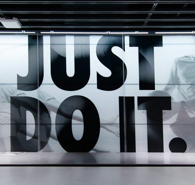 Nike store interior with a large “Just Do It” slogan over black-and-white athlete images behind a counter.