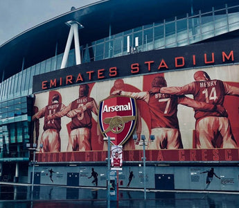 The exterior of Arsenal’s Emirates Stadium in London, featuring a large mural of former Arsenal players, used to illustrate workplace culture and team identity in recruitment decisions.