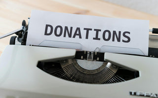 Vintage typewriter holding a sheet of paper with the word “DONATIONS” in bold black letters.