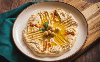 Creamy hummus topped with olive oil, chickpeas and spices served on a plate, illustrating the rise of plant-based foods in UK consumer spending and inflation trends