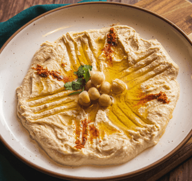 Creamy hummus topped with olive oil, chickpeas and spices served on a plate, illustrating the rise of plant-based foods in UK consumer spending and inflation trends