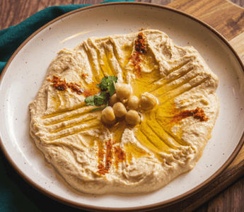 Creamy hummus topped with olive oil, chickpeas and spices served on a plate, illustrating the rise of plant-based foods in UK consumer spending and inflation trends