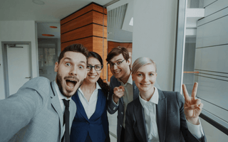 A group of cheerful young professionals taking a selfie together in a modern office — symbolising workplace friendships, collaboration, and the human connection explored in KPMG’s Friends at Work 2.0 report.