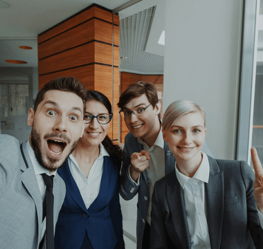 A group of cheerful young professionals taking a selfie together in a modern office — symbolising workplace friendships, collaboration, and the human connection explored in KPMG’s Friends at Work 2.0 report.