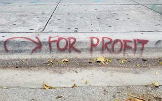 Graffiti on a pavement reading “For Profit” with an arrow, symbolising the focus on profit over long-term business strength.