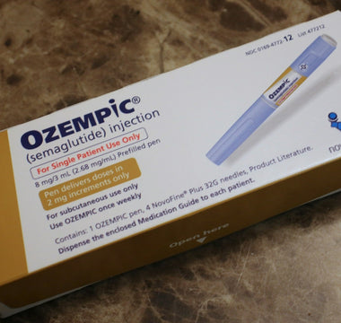 Close-up of an Ozempic injection medication box on a marble surface, showing the branded packaging and injectable pen used for diabetes and weight-loss treatment.