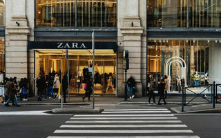 Shoppers outside a Zara store with large display windows and a pedestrian crossing in the foreground.