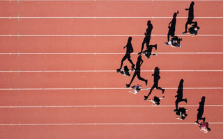 Sprinters racing in a 100m track event, representing how businesses compare their performance against industry benchmarks.