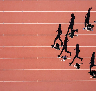 Sprinters racing in a 100m track event, representing how businesses compare their performance against industry benchmarks.