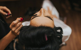Close-up of a woman having mascara applied during a beauty treatment, representing the global cosmetics and fragrance industry discussed in the article.