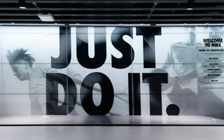 Nike store interior with a large “Just Do It” slogan over black-and-white athlete images behind a counter.