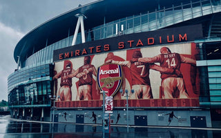 The exterior of Arsenal’s Emirates Stadium in London, featuring a large mural of former Arsenal players, used to illustrate workplace culture and team identity in recruitment decisions.