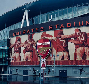 The exterior of Arsenal’s Emirates Stadium in London, featuring a large mural of former Arsenal players, used to illustrate workplace culture and team identity in recruitment decisions.
