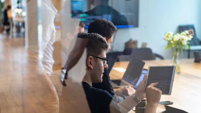 Students collaborating in a modern workspace using laptops and tablets, representing the dual qualification pathway where academic and professional learning are combined for enhanced career outcomes.