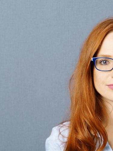 Confident professional woman with red hair and blue glasses standing against a grey background — used as the main banner image for ExP’s online ACCA, CMA, DipIFR and FIA courses.