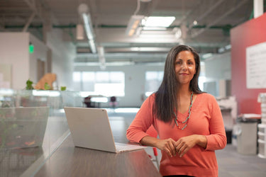 Woman standing in an office with a laptop on a desk