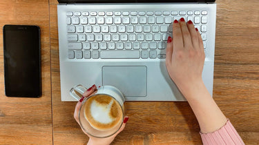 Student using a laptop with coffee on a wooden desk, representing ExP’s free 7-day trial for ACCA, CMA, DipIFR and FIA online courses.