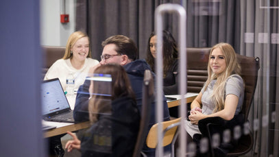 A group of adult learners engaged in a collaborative classroom session with laptops, symbolising flexible bridge and fast-track programmes designed for professionals advancing their qualifications.
